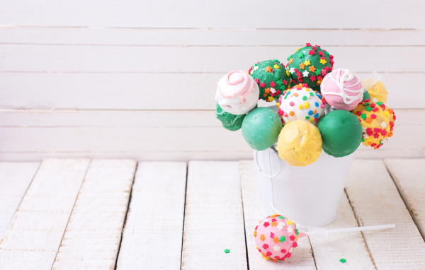 Разноцветные леденцы на палочке в белом ведерке