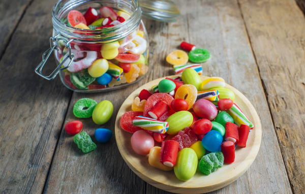 Разноцветные мармеладные конфеты в стеклянной банке на столе