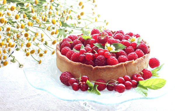 Пирог с ягодами малины и смородины на столе с ромашками