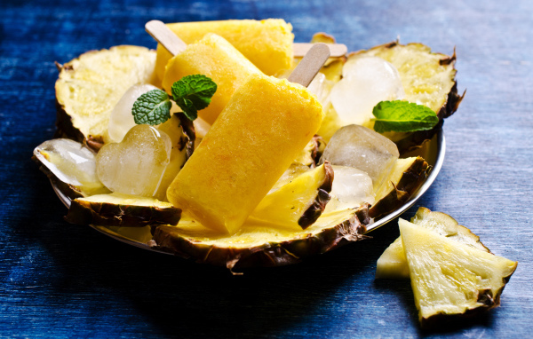 Ананасовое мороженое со льдом лежит на кусочках свежего ананаса