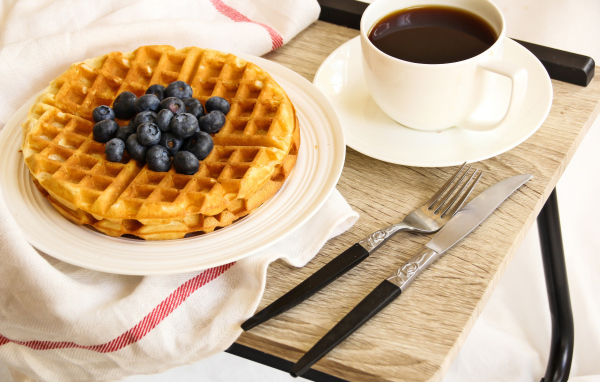 Сладкие вафли с черникой и чашкой кофе на завтрак