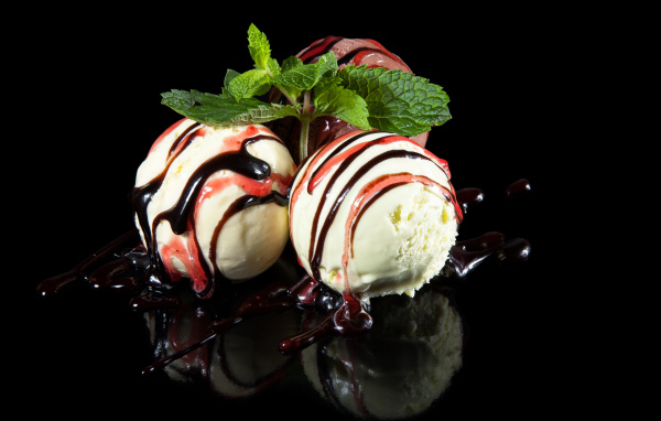 Три шарика мороженого с джемом на черном фоне