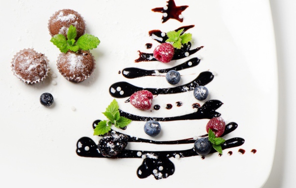 Три кекса и нарисованная шоколадом елка на белой тарелке