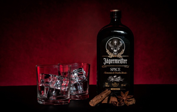 Бутылка ликера Jägermeister на столе с корицей и стаканами