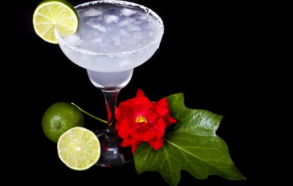Бокал коктейля со льдом и лаймом на черном фоне