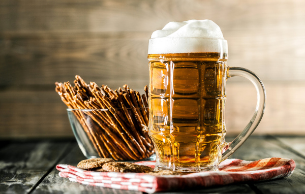 Бокал свежего пива с выпечкой на столе