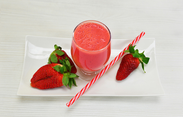 Бокал клубничного коктейля со свежей клубникой и трубочкой