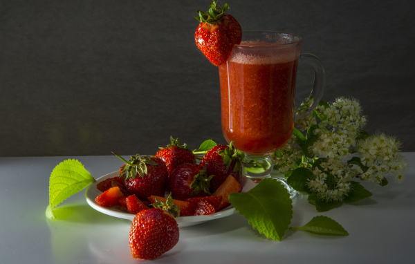 Стакан клубничного сока и свежая клубника на столе