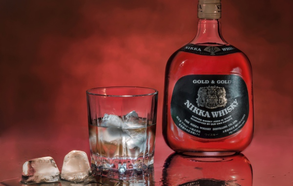Бутылка Nikka Whisky на столе со стаканом со льдом