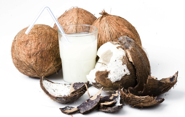 Кокосовое молоко в стакане и кокосы на белом фоне
