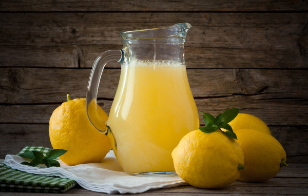 Свежевыжатый лимонад в стеклянном кувшине на столе
