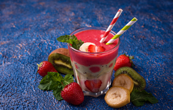 Фруктовый коктейль с клубникой, бананом и киви в стакане с трубочками