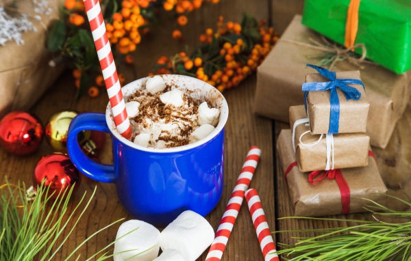 Сладкий напиток с маршмеллоу на столе с подарками на Новый год