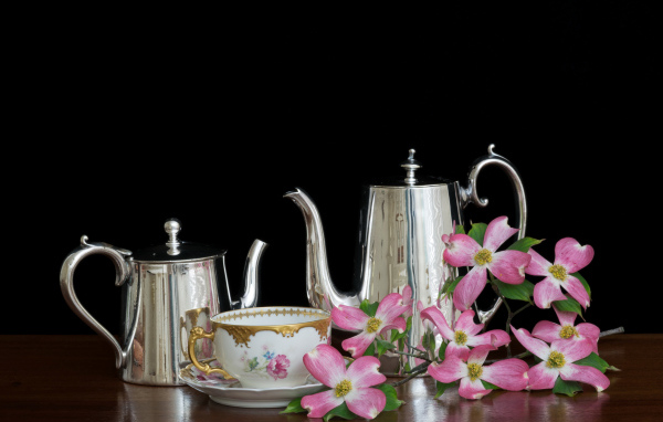 Чайники с чашкой с цветами на столе на черном фоне