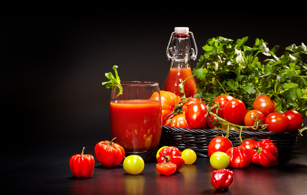 Томатный сок и свежие помидоры на столе на черном фоне
