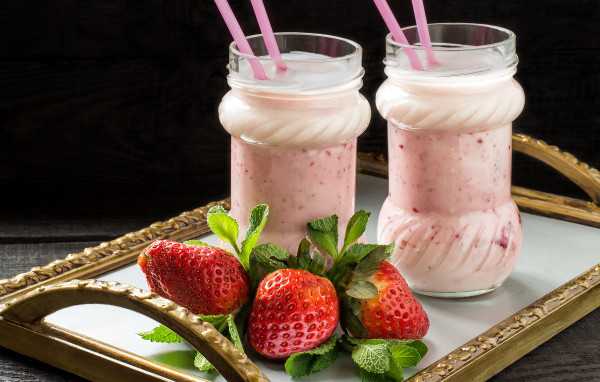 Два свежих клубничных коктейля с трубочками и ягодами клубники