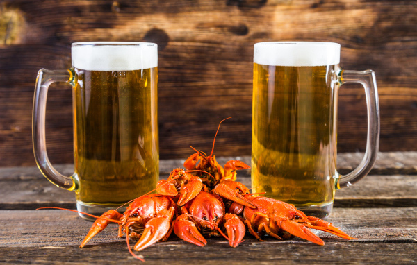 Два бокала пива с красными раками на столе