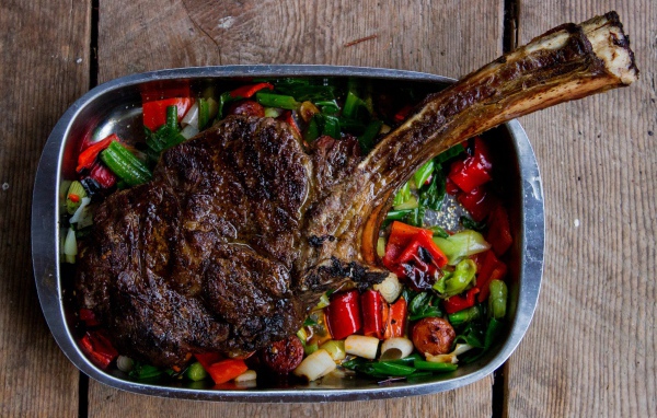 Кусок жареного мяса на ребрышке с овощами