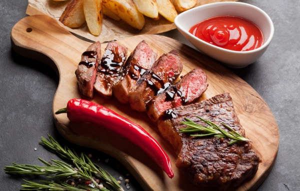 Аппетитный сочный стейк с соусом, красным перцем и специями на столе