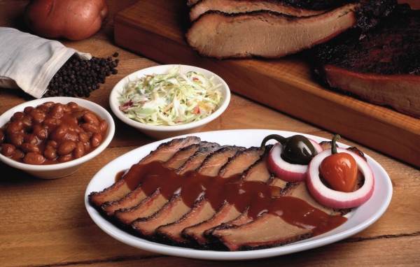 Аппетитные кусочки мяса барбекю на столе с овощами