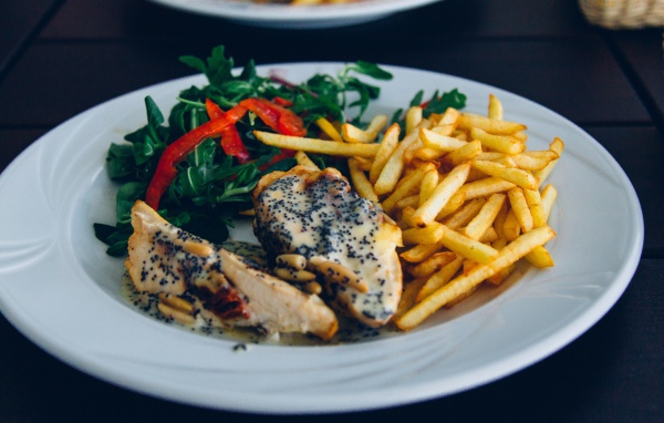 Курица с картофелем фри и салатом на большой белой тарелке