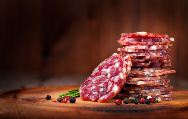 Нарезанная сухая колбаса на столе со специями