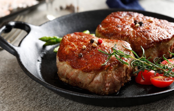 Два аппетитных сочных куска мяса с помидорами и розмарином