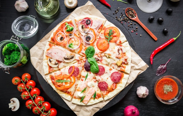 Аппетитная пицца на столе со специями и помидорами