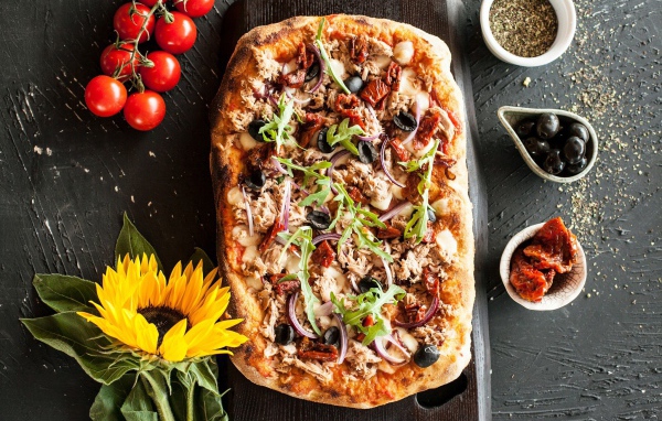 Жареная пицца с мясом на столе с желтым цветком подсолнуха