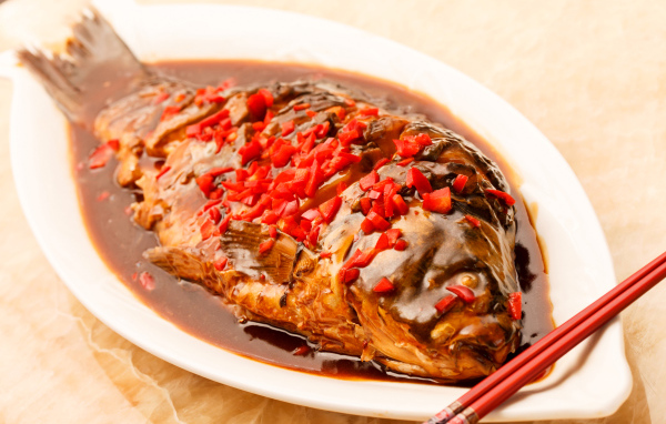 Жареная рыба с соусом и красным перцем в белом блюде