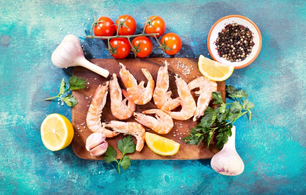 Креветки на разделочной доске с чесноком, лимоном и специями