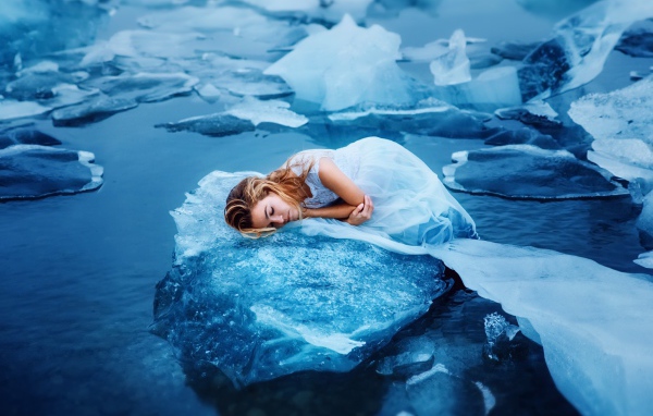 Девушка в красивом белом платье лежит на льдине