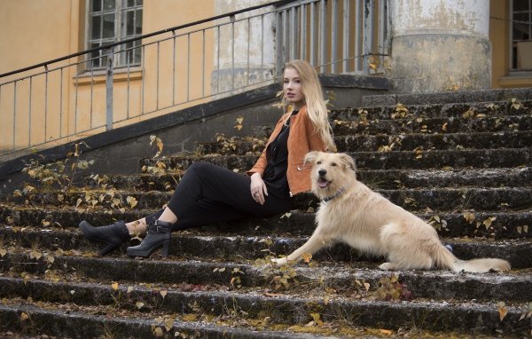 Молодая девушка сидит с собакой на старых ступеньках