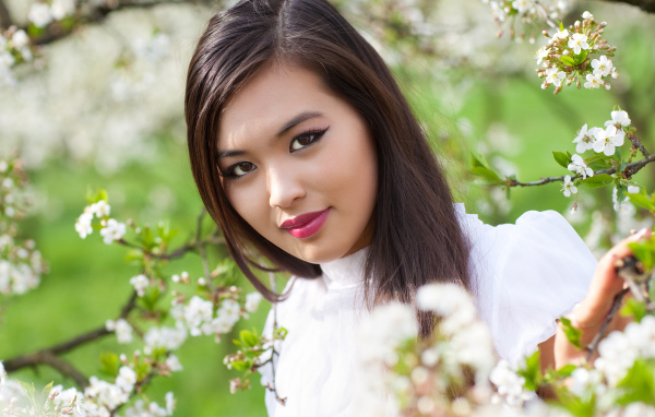 Красивая девушка азиатка в ветках цветущего дерева