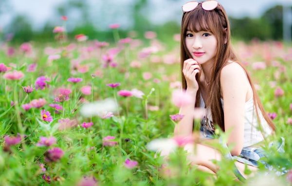 Красивая девушка модель азиатка на поле с розовыми цветами