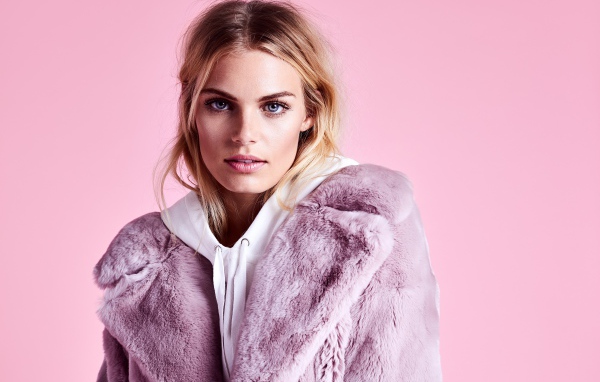 Красивая голубоглазая девушка в шубе на розовом фоне