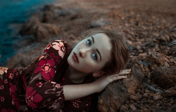 Красивая голубоглазая девушка лежит на камне 