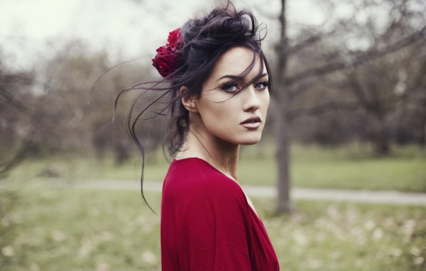 Красивая брюнетка в красном платье с цветком в волосах