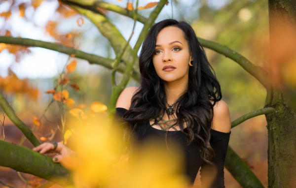 Красивая брюнетка у дерева в черном платье