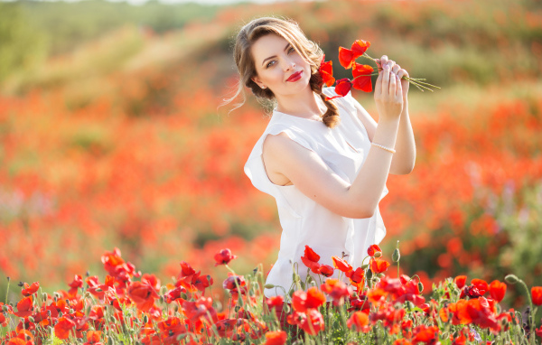 Красивая девушка в белом платье с букетом маков в руках