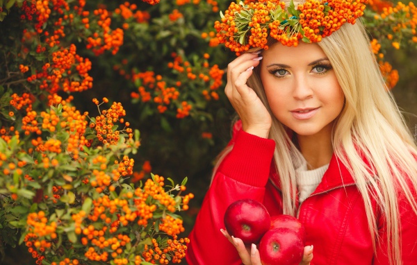 Красивая девушка с венком из рябины на голове и с красными яблоками в руках 