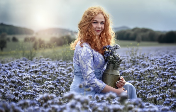 Красивая рыжеволосая девушка собирает цветы