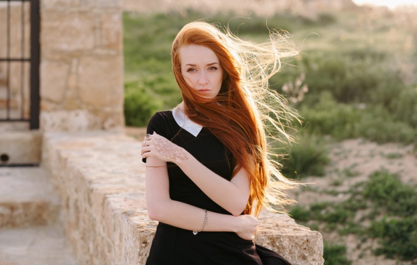 Красивая рыжеволосая девушка в черном платье с рисунком на руке