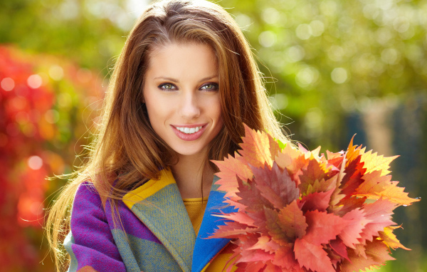 Красивая улыбающаяся девушка с букетом желтых листьев в руке