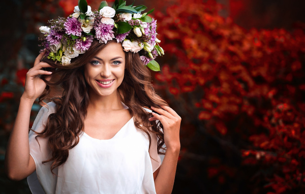 Красивая улыбающаяся девушка с венком из живых цветов на голове 
