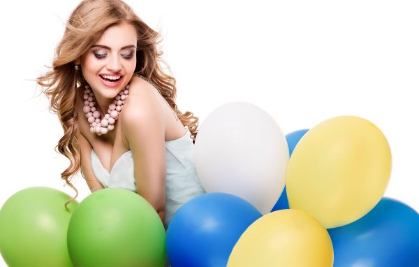 Красивая улыбающаяся девушка с разноцветными шариками на белом фоне
