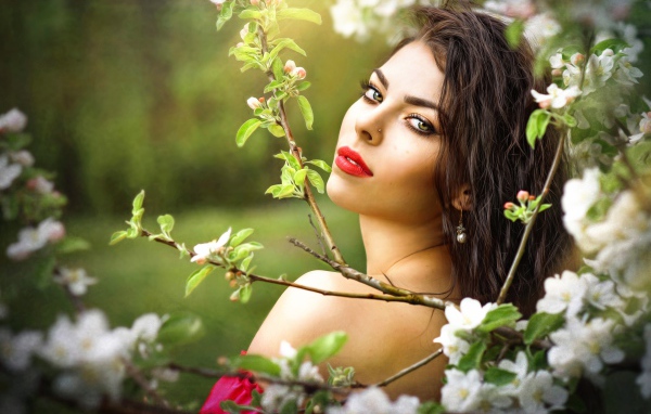 Красивая молодая девушка в ветках цветущей яблони 