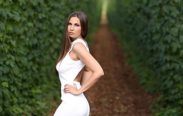 Красивая молодая девушка с длинными волосами в белом платье