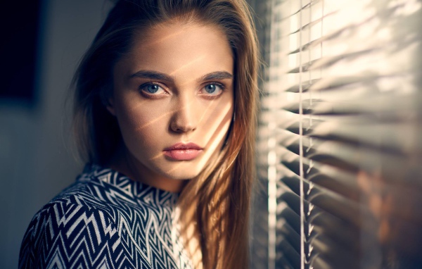 Девушка блондинка с голубыми глазами у окна 