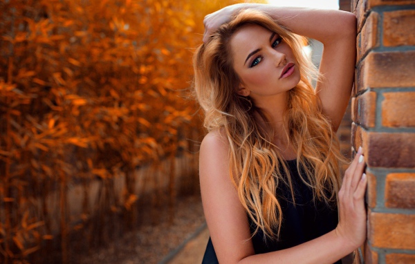 Голубоглазая девушка блондинка у стены 